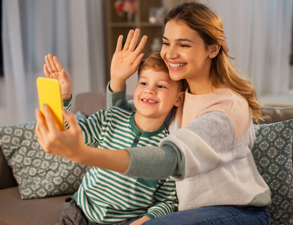 Photo showing a Mother and son waving at a mobile phone