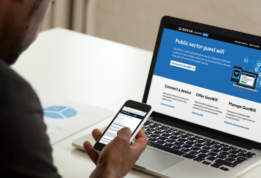 Man viewing the GovWifi BETA website on a laptop and a mobile phone