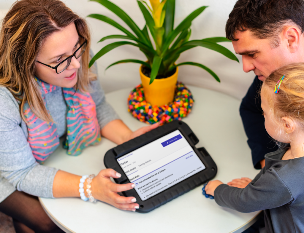 Photo of a woman showing a tablet screen to a man and a child