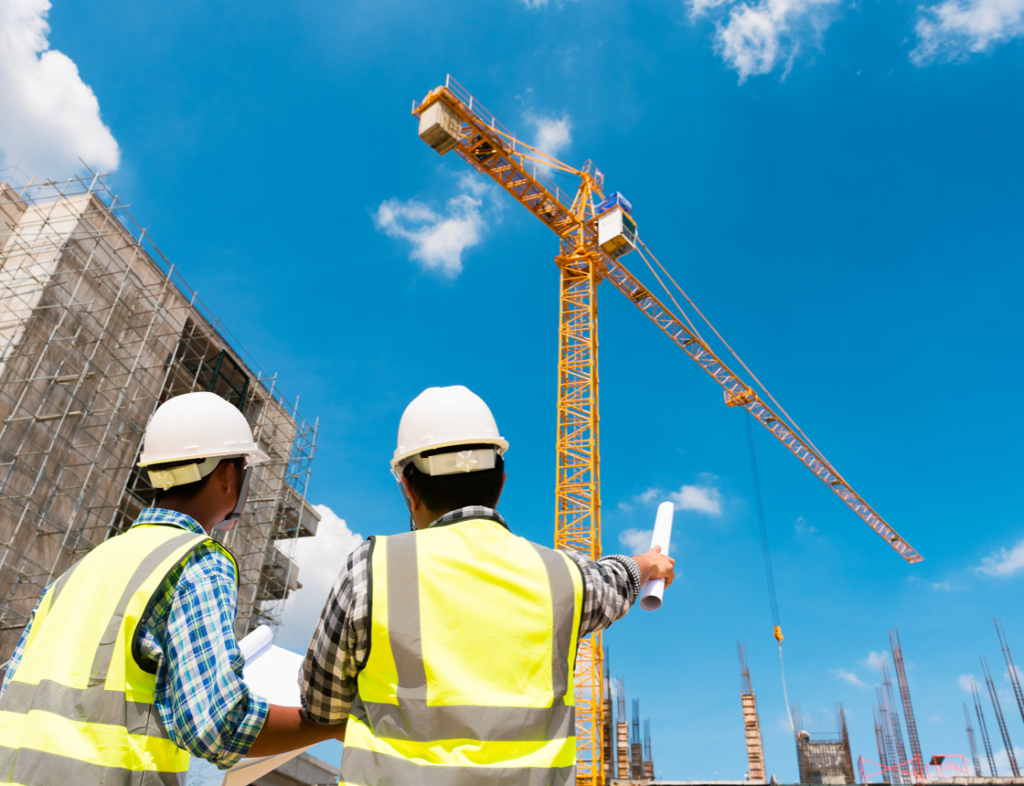 Photo showing two builders looking up at a crane on a construction site