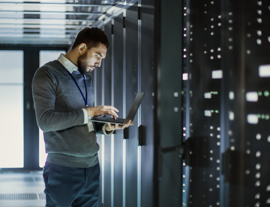 Photo showing a man using a laptop next to a server