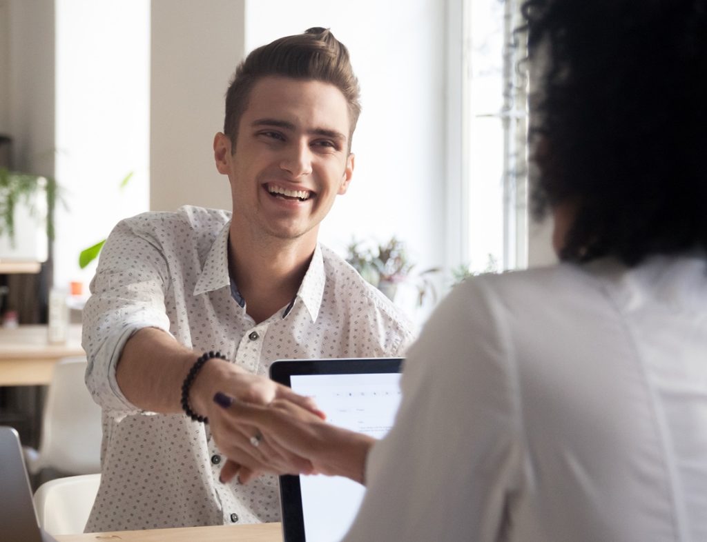 Photo showing a man shaking hands with someone across the table