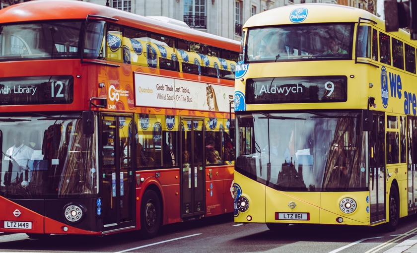 Photo showing two double decker london busses, one is red, and one is yellow