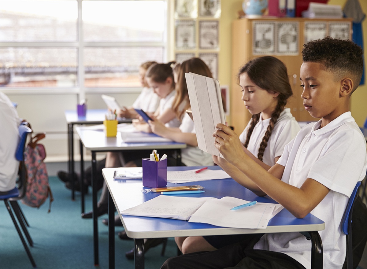 Photo showing children in a classroom working on tablets