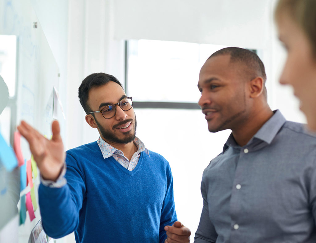 Photo of a man explaining something to a group of people 