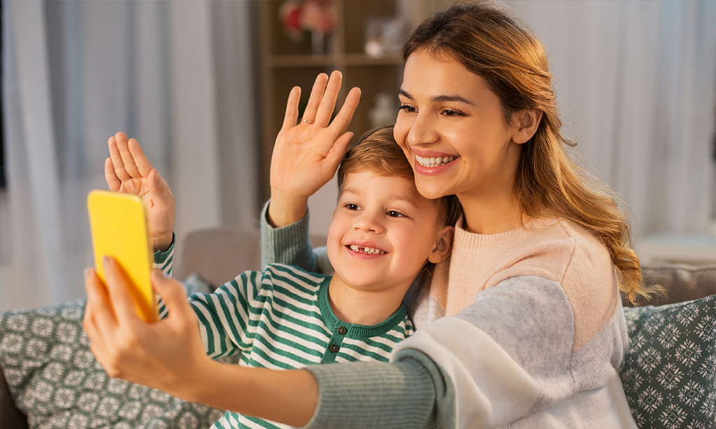 Image of woman and boy smiling and waving at a phone
