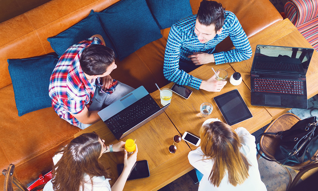 Image of a group of people sitting in front of laptops around a table