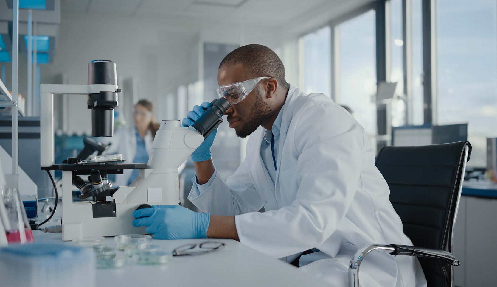 Image of person sitting at a table in a medical laboratory looking into a microscope