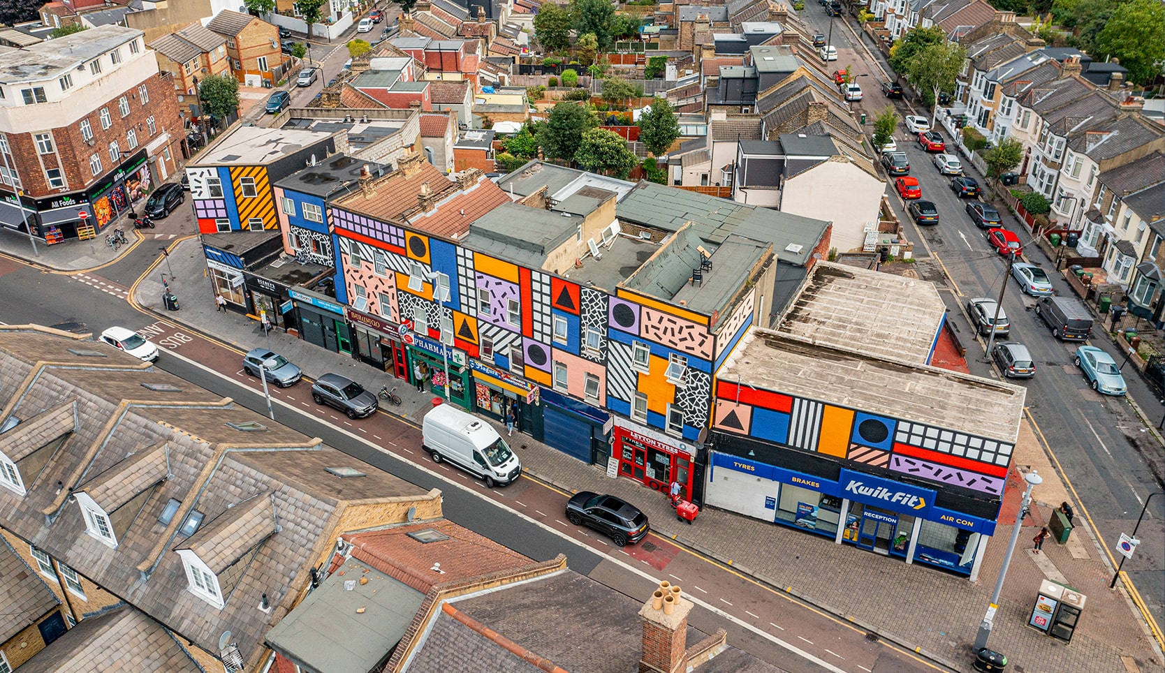 Aerial photo from a drone of Leyton High Street, High Road, Leyton, East London, Waltham Forest, London, UK. Including Walala Parade artwork on building.