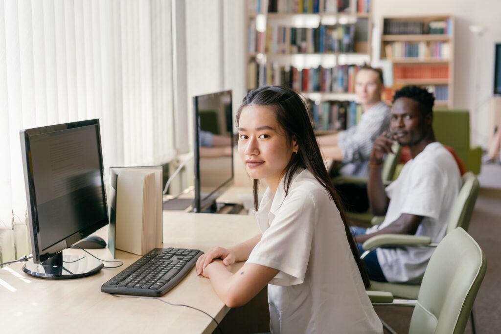 Three people sitting at computers in a library.