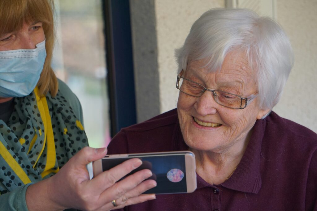 Woman and care worker looking at mobile phone.
